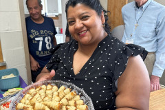 Smiling woman holding a circular plate of delicious homemade sandwiches.