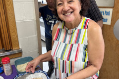 Smiling older adult holding a plate of delicious homemade food.