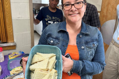 Smiling woman holding a bowl of delicious homemade sandwiches.