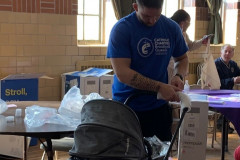 Catholic Charities Brooklyn and Queens volunteer  in a blue shirt sets up a stroller.