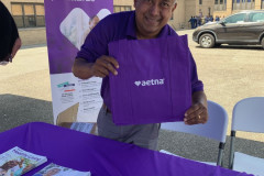 A man holding a purple bag over a purple table from Aetna.