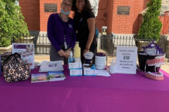 A couple of women standing next to a purple table from Liberty Dental Plan.