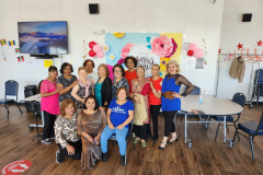 Members of an older adult center are seated  in  front of a floral backdrop ,