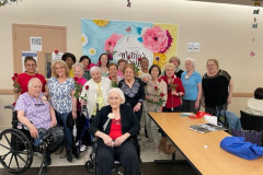Members and faculty are seated for a group photo during a Mother's Day celebration .